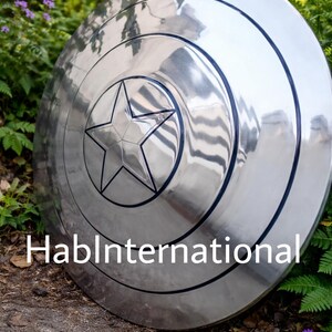 May include: A silver-colored shield with a central star design and concentric circles. The shield has a reflective surface and a black outline around the star. The text "HablInternational" is visible on the shield.