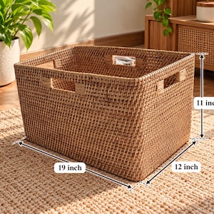 May include: A rectangular woven storage basket with integrated handles, featuring a natural tan finish. The basket measures 48.26 cm in length, 30.48 cm in width, and 27.94 cm in height, as indicated by the visible dimension labels on the image.