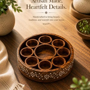 May include: A round, wooden spice box with multiple compartments. The box is dark brown with white floral designs around the rim. The text "Artisan Made, Heartfelt Details" is at the top of the image.