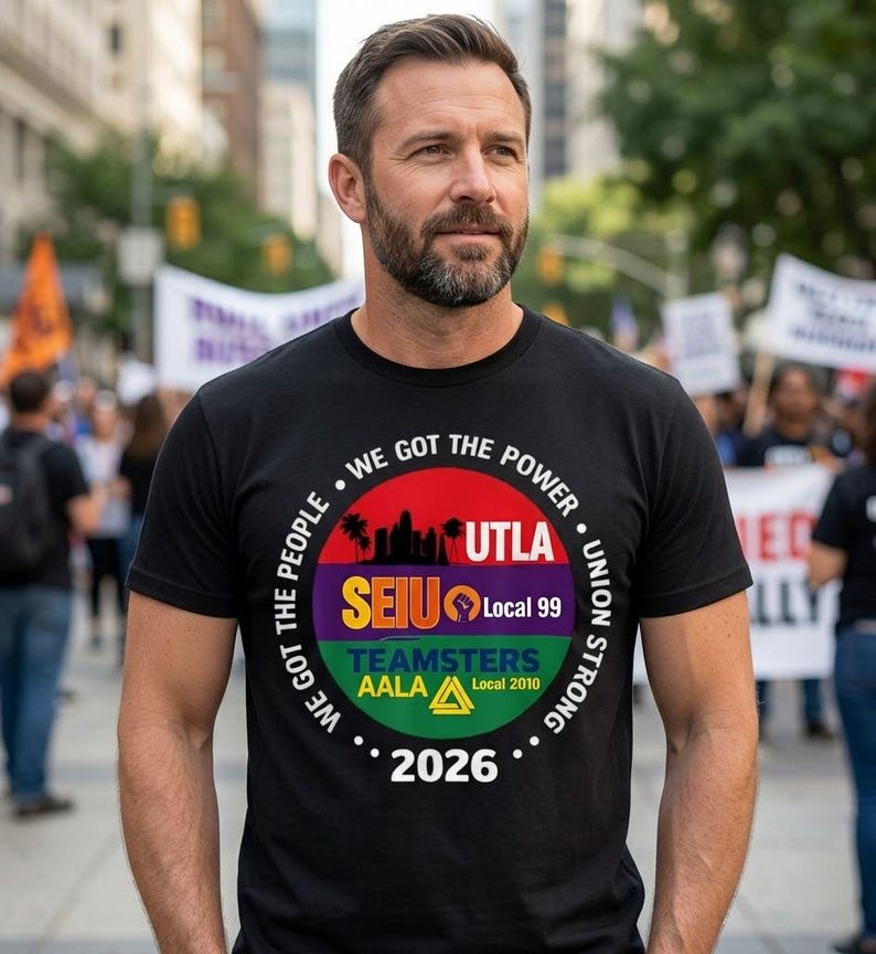 May include: Black t-shirt with a circular graphic featuring the text "WE GOT THE POWER" and "UNION STRONG." The graphic includes the text "UTLA," "SEIU Local 99," "TEAMSTERS AALA Local 2010," and the year "2026." The shirt is worn by a person.
