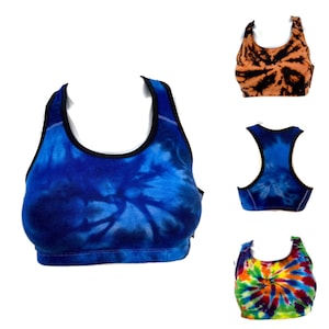 Può includere: Tre reggiseni sportivi tie-dye in diverse combinazioni di colori. Il primo reggiseno è blu e nero, il secondo è arancione e nero, e il terzo è un arcobaleno di colori.