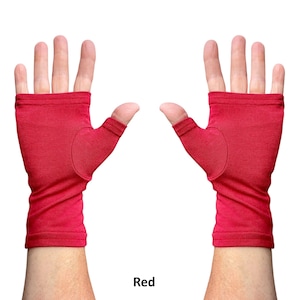 May include: A pair of fingerless gloves in a solid red color. The gloves feature an open-finger design that exposes the fingers while covering the palm and wrist area. The fabric appears to be a soft, smooth knit material with stitched hems.