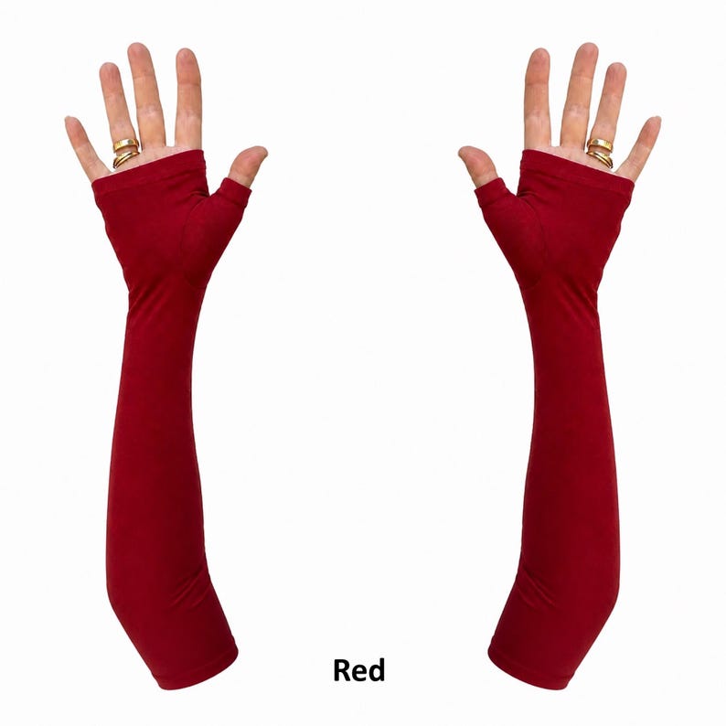 May include: A pair of deep red, long, fingerless gloves that extend past the elbow. The fabric is smooth and solid in colour, covering the forearm and palm while leaving the fingers exposed. The word Red is printed in black text below the gloves.