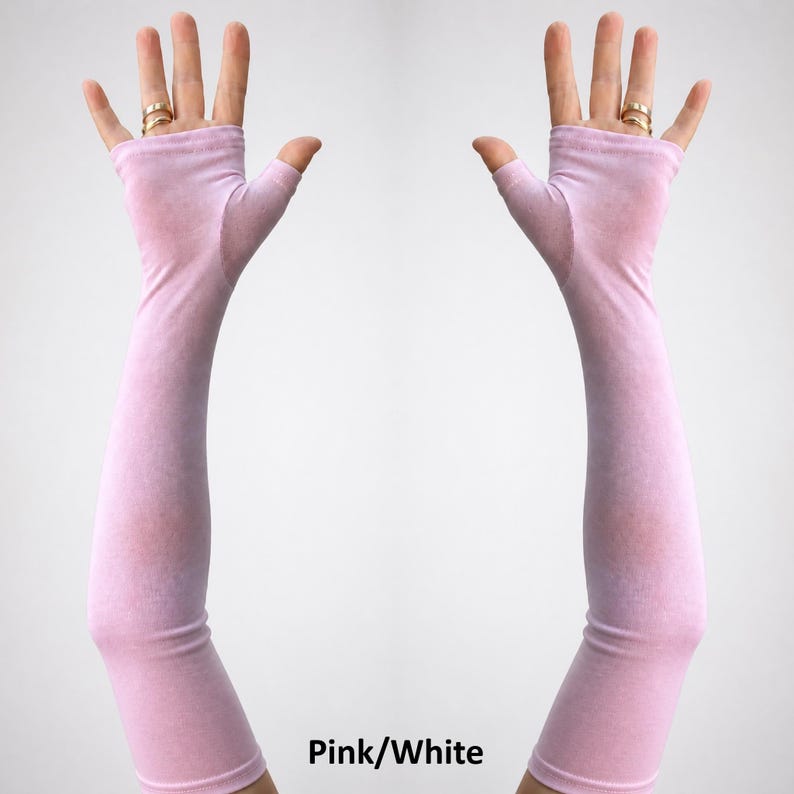 May include: A pair of long, fingerless gloves in a light pink hue, extending from the knuckles up to the mid-forearm. The fabric appears smooth and lightweight, covering the palm and wrist while leaving the fingers exposed. Text reads Pink/White.