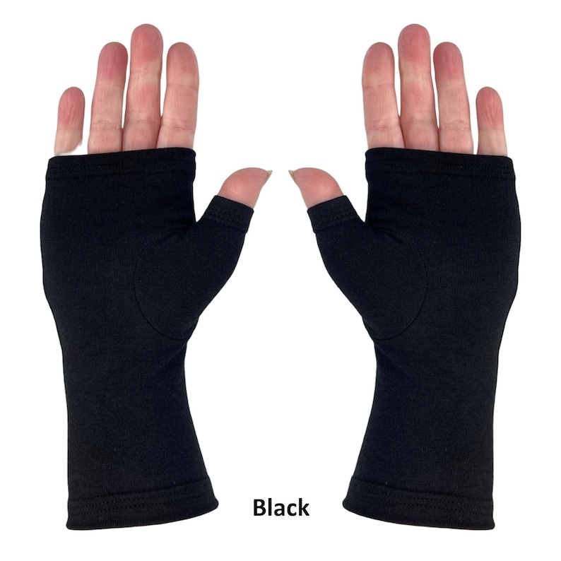 May include: A pair of solid black fingerless gloves featuring a thumb hole and an open-finger design. The gloves extend from the base of the fingers to the wrist, constructed from a smooth, opaque fabric with finished stitched edges at the openings.