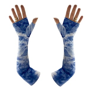 Puede incluir: Un par de mangas de brazo teñidas con tinte azul y blanco. Las mangas no tienen dedos, con un agujero para el pulgar y una manga larga que se extiende por el brazo. La tela tiene un patrón de nubes en tonos azules y blancos.