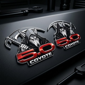 May include: Two metallic car emblems featuring a wolf in a hooded cloak holding a scythe. The emblems have a red "5.0" and "COYOTE" text on a black background. The wolf has gray fur and is set against a dark background.
