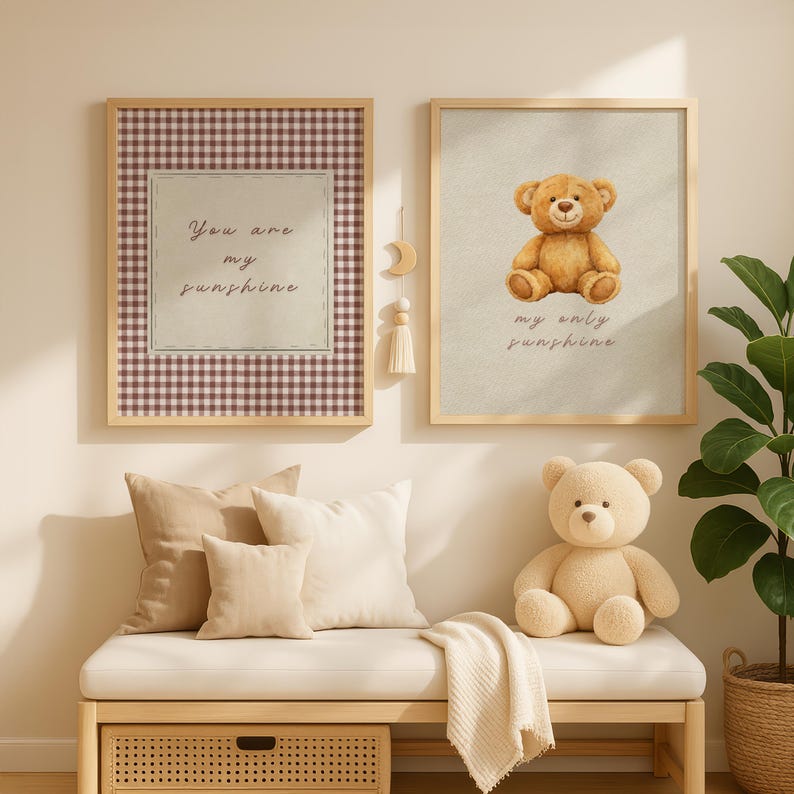 May include: Two framed prints with the text "You are my sunshine" and a teddy bear illustration. A plush teddy bear sits on a bench with pillows and a blanket. The prints have wooden frames and are in a nursery setting.