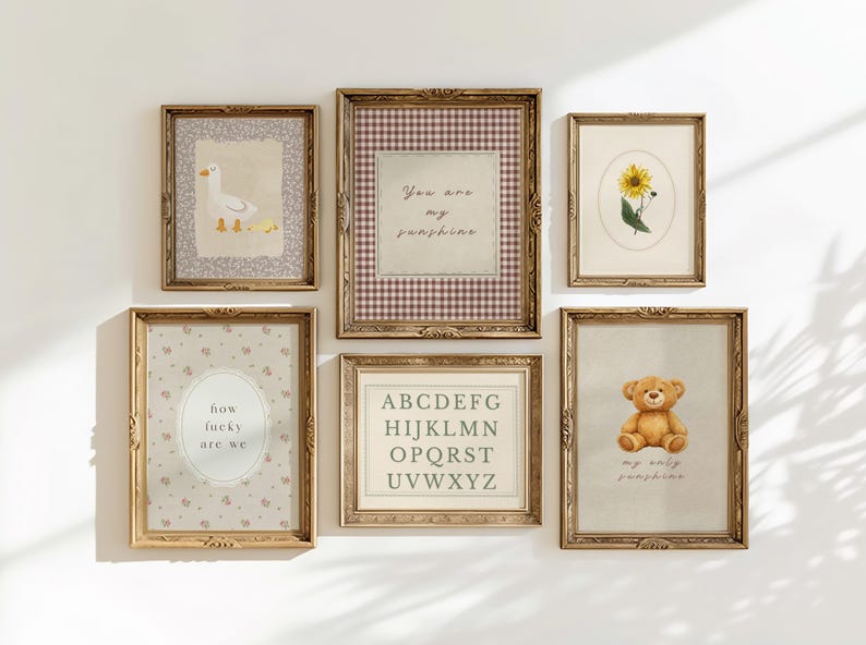 May include: A collection of framed art prints with vintage-style designs. The prints feature a goose with ducklings, a sunflower, a teddy bear, an alphabet, and text that reads "You are my sunshine" and "how lucky are we". The frames are gold-colored.