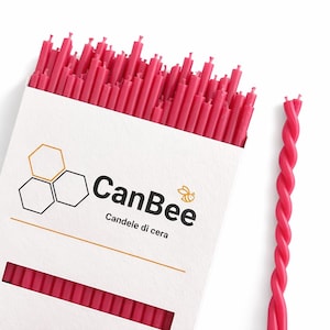 May include: A box of bright pink candles with the text "CanBee" and "Candele di cera" printed on the front. A single twisted pink candle is next to the box. The box has a honeycomb design.