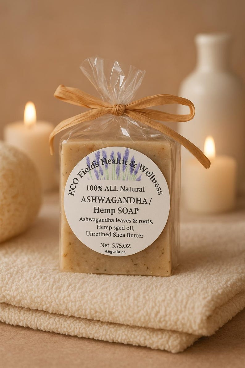 以下が含まれることがあります： 「100% ALL Natural ASHWAGANDHA / Hemp SOAP」と書かれたラベルが付いた、アシュワガンダとヘンプの石鹸が包まれています。石鹸は透明なセロファンで包装され、ラフィアのリボンで結ばれています。正味重量は163グラムです。