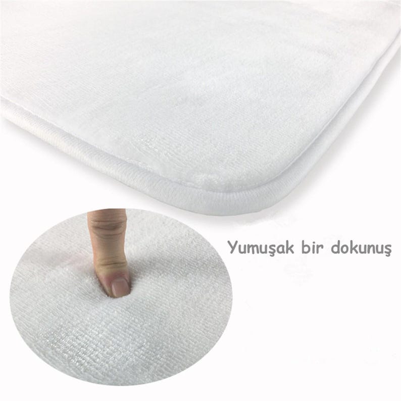 Puede incluir: Una alfombrilla de ba&ntilde;o rectangular de color blanco con una textura suave y afelpada. La imagen incluye un recuadro circular que muestra el material siendo presionado, demostrando su superficie acolchada, junto al texto Yumuşak bir dokunuş.