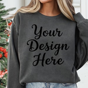 Könnte beinhalten: Dunkelgraues Sweatshirt mit dem Text "Your Design Here" in schwarzer Schrift. Das Sweatshirt hat einen Rundhalsausschnitt und scheint aus einem weichen Material zu sein. Der Stil ist lässig und bequem.