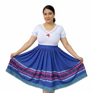 May include: A white top with a V-neck and red embroidery, paired with a blue skirt. The skirt features a decorative pink and white pattern and a lace trim. The outfit is a dress.