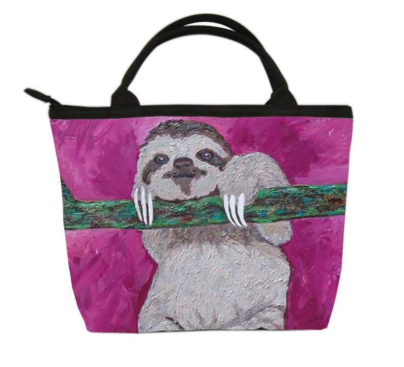 May include: A pink tote bag with a painting of a sloth hanging from a branch. The sloth has a light brown fur and white claws. The background is a bright pink color.