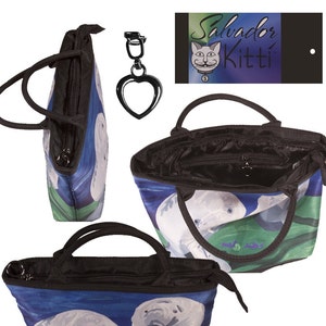 May include: A black tote bag with a zipper closure and two handles. The bag features a colorful print of two manatees swimming in blue water with green plants. The bag comes with a matching heart-shaped keychain.