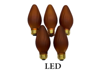 May include: A set of five brown, frosted, flame-shaped LED light bulbs with gold-colored metal screw bases. The bulbs feature a textured, ribbed surface design and are arranged in a cluster. The text LED is printed in black below the bulbs.