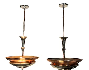 May include: A pair of ceiling pendant lights featuring amber-colored, ribbed glass bowls suspended by polished chrome metal rods. Each fixture includes a central stem, a flared decorative element, and a small finial at the bottom.