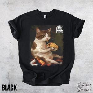 May include: Black t-shirt featuring a cat eating a taco, with a bottle of hot sauce and the Taco Bell logo. The cat is brown and white. The word "BLACK" is printed at the bottom left.