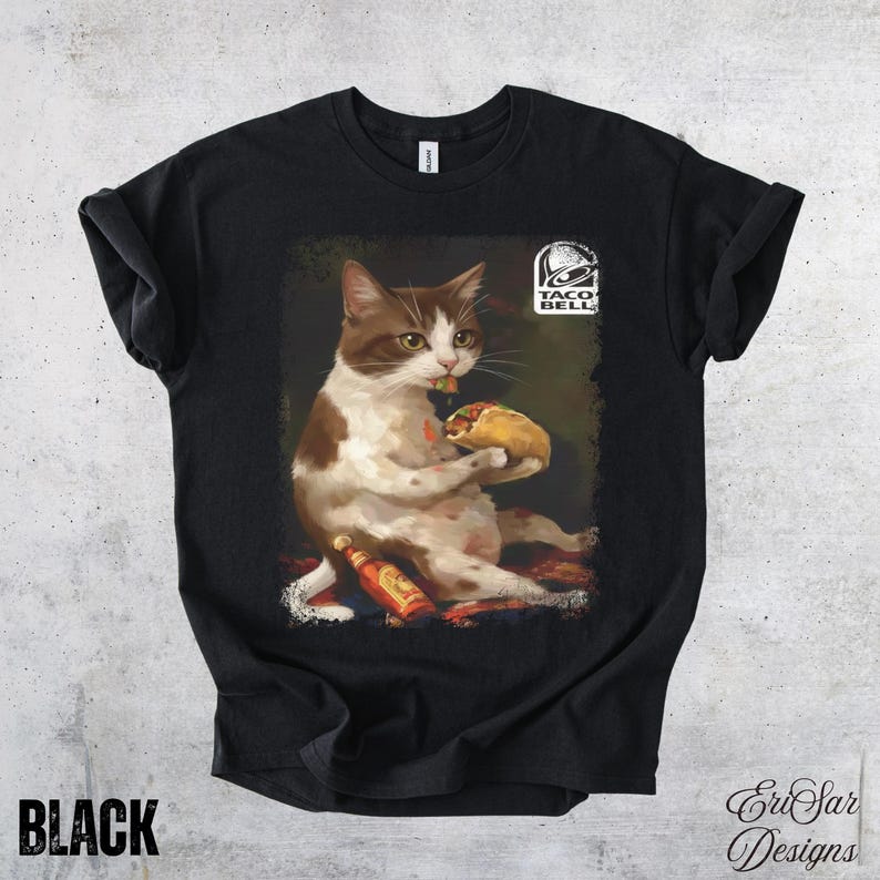 May include: Black t-shirt featuring a cat eating a taco, with a bottle of hot sauce and the Taco Bell logo. The cat is brown and white. The word "BLACK" is printed at the bottom left.