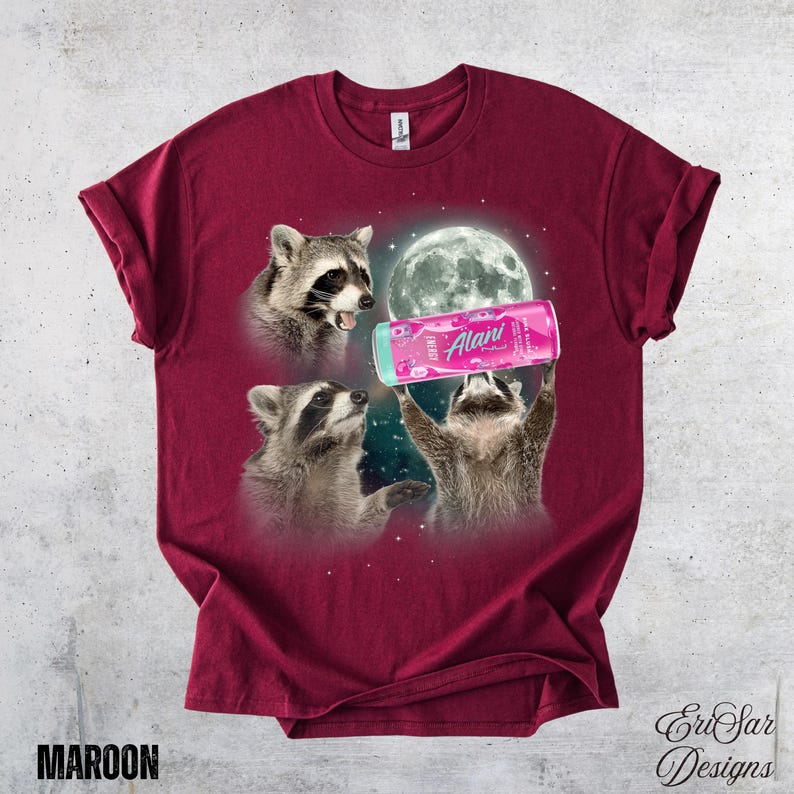 May include: Maroon t-shirt featuring a whimsical design of three raccoons with a full moon backdrop. One raccoon holds a pink Alani Energy drink can. The shirt has the word "MAROON" printed at the bottom.