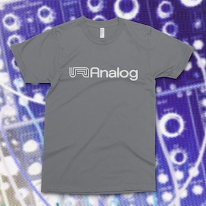 May include: A white ceramic mug with a black handle and the text "But First, Coffee" in a bold, black font. The mug is set against a blurred background, suggesting a cozy setting.