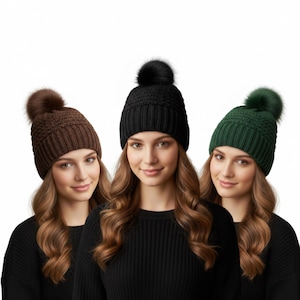 May include: Three women wearing knitted beanies with faux fur pom-poms. The beanies are in brown, black, and green. The women are wearing black sweaters. The background is white.