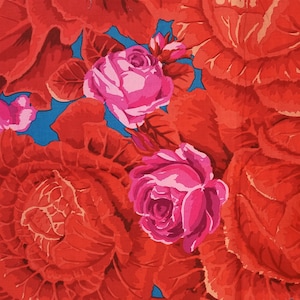 May include: A vibrant floral print fabric featuring large red cabbage roses with pink centers. The background is a bright turquoise blue.