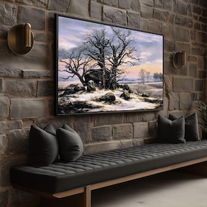 Puede incluir: Una pintura de paisaje enmarcada representa árboles desnudos y suelo cubierto de nieve. La obra de arte está colgada en una pared de ladrillo, encima de un banco negro con cojines grises. Dos apliques de latón flanquean la pintura.