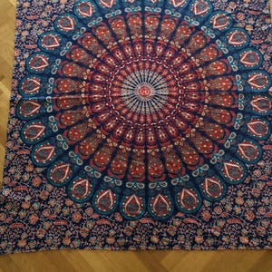May include: A blue tapestry with a large, colorful mandala design. The mandala features intricate patterns in shades of red, orange, blue, and green.