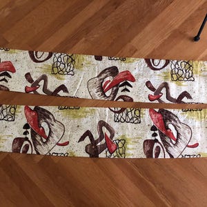 May include: Two rectangular fabric panels featuring an off-white background with a repeating abstract pattern. The design includes curved brown shapes, solid red accents, black line-art grids, and muted olive green splatters across the surface.