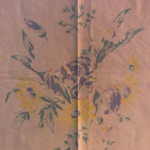 May include: A white tablecloth with a floral pattern featuring yellow and purple flowers and green leaves.
