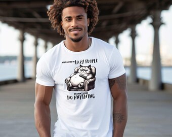 Könnte beinhalten: Weißes T-Shirt mit einer Grafik einer Katze in einem Sessel mit Fernbedienung. Der Text auf dem Shirt lautet: "Stop Hating on Lazy People, We Didn't Even Do Anything."