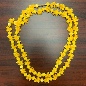 Colar longo vintage de plástico amarelo com contas de flor de lis dos anos 1960