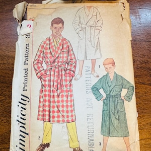 May include: Vintage Simplicity printed pattern envelope featuring illustrations of bathrobes. The envelope shows three different robe designs, including a red plaid robe, a white robe, and a green robe. The text "Simplicity Printed Pattern" is visible.
