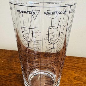 May include: Clear glass cocktail shaker with black printed recipes for Manhattan and Whisky Sour cocktails. Includes measurements and instructions for mixing drinks. A vintage barware item.