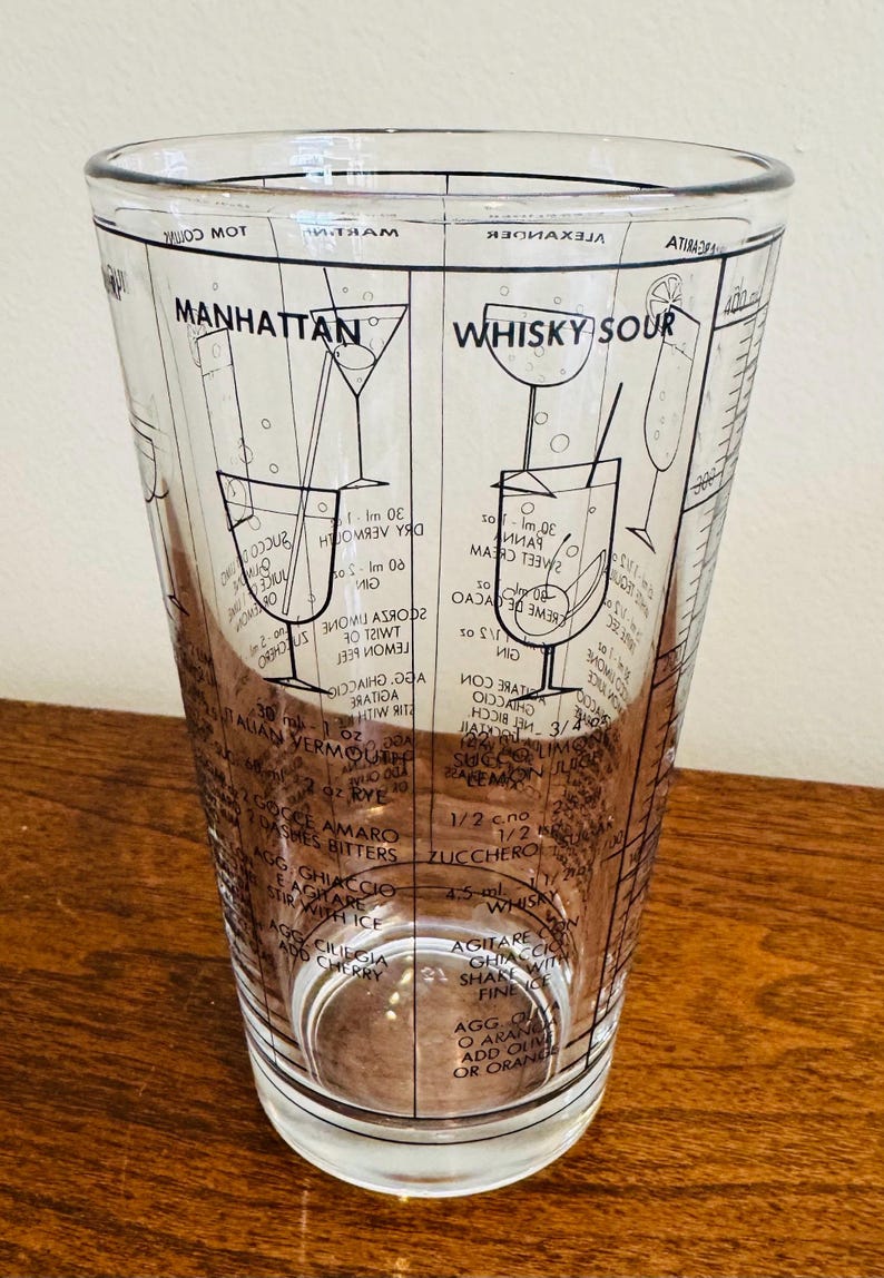 May include: Clear glass cocktail shaker with black printed recipes for Manhattan and Whisky Sour cocktails. Includes measurements and instructions for mixing drinks. A vintage barware item.