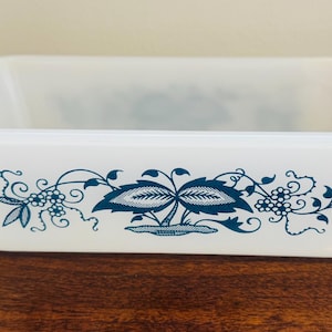 Peut inclure: Plat à four rectangulaire blanc aux coins arrondis. Le plat présente un motif floral bleu sarcelle avec un motif central de fraise. Le motif est répété sur le devant. Le plat est en matériau durable et résistant à la chaleur.