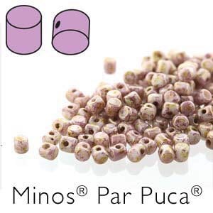 May include: A pile of Minos Par Puca beads in shades of beige and lavender. The beads are cylindrical with a hole running through the center. Two illustrative examples of the beads are shown in the upper left corner.