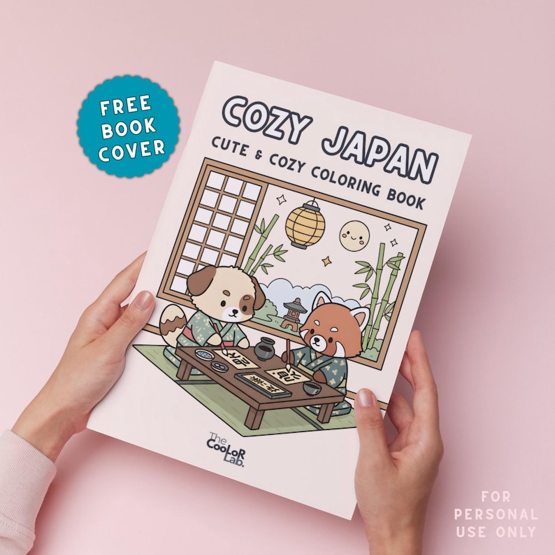 以下が含まれることがあります： 「COZY JAPAN」というタイトルの塗り絵本を人が持っています。「CUTE & COZY COLORING BOOK」というサブタイトルです。表紙には、日本の衣装を着た犬とレッサーパンダのイラストが描かれています。水色のステッカーには「FREE BOOK COVER」と書かれています。