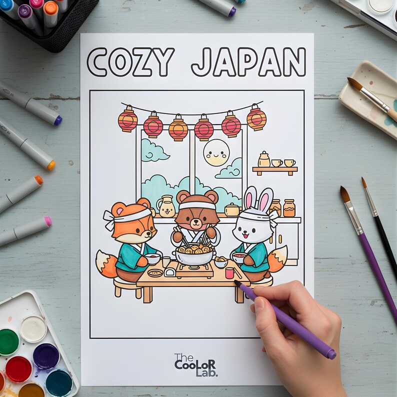 以下が含まれることがあります： 「COZY JAPAN」の文字が上部にある塗り絵。イラストには、キツネ、クマ、ウサギの3匹の漫画の動物が、食事を楽しんでいる様子が描かれています。日本のスタイルの部屋で、提灯が飾られています。