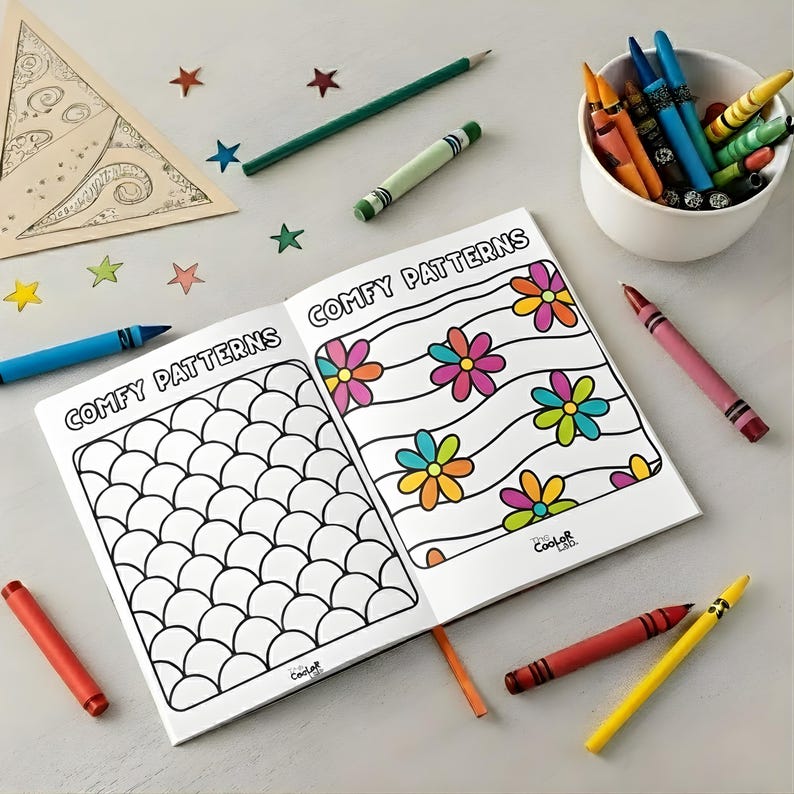 May include: An open coloring book with the words "COMFY PATTERNS" on the cover, featuring flower and scale designs. Crayons, colored pencils, and star-shaped confetti surround the book, with a small bowl of crayons in the background.