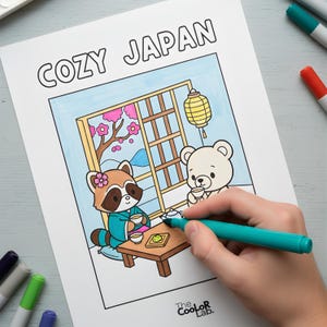 以下が含まれることがあります： 「COZY JAPAN」の文字が上部にある塗り絵。イラストは、日本のスタイルの部屋でお茶を飲むアライグマとクマを描いています。手はターコイズ色のマーカーで画像を塗っています。Coolor Labのロゴが下にあります。