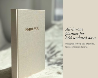 May include: A beige fabric-covered planner with the text INSIDE YOU embossed on the front cover. The text on the right side reads All-in-one planner for 365 undated days. Designed to help you organize, focus, reflect and grow.