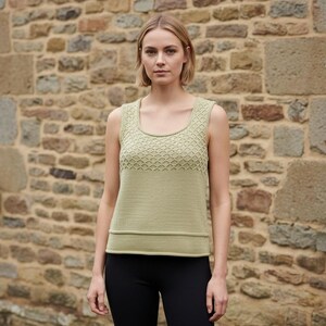 May include: A light green tank top with a square neckline and a textured, geometric pattern on the upper chest. The bottom half of the top has a horizontal ribbed design. The model is wearing black pants.