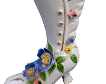 Jarrón decorativo de porcelana en forma de bota con flores aplicadas y ribete dorado, estilo vintage.