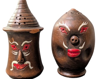 Juego de salero y pimentero de arte popular vintage con caras pintadas a mano, estilo rústico.