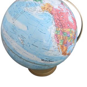 May include: A Replogle World Nation globe with a gold-colored base and meridian. The globe features a detailed map with blue oceans and colorful continents. The text "Tropic of Cancer" is visible. The globe is a classic educational tool.