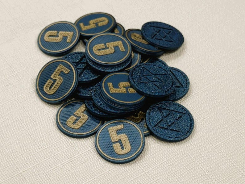A pile of metallic blue, circular game coins worth five coins. The coins have a raised "3" on the front and a submerged symbol on the back. These premium board game coins replace the standard card board coins.