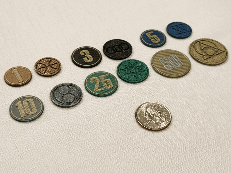 Generic Board game coins with various denominations, including 1, 3, 5, 10, 25 and 50. The coins feature various designs, including numbers, symbols, and logos, in colors like gold, green, black, and blue. A quarter is provided for scale.